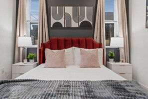 A bedroom with a large bed, two bedside tables, a red upholstered headboard, and a wall-mounted artwork. - University City 1BR | Zoo, UPenn & Museums (Philadelphia)