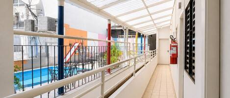 Un pasillo con techo de vidrio, una zona de piscina con toboganes y un extintor en la pared.