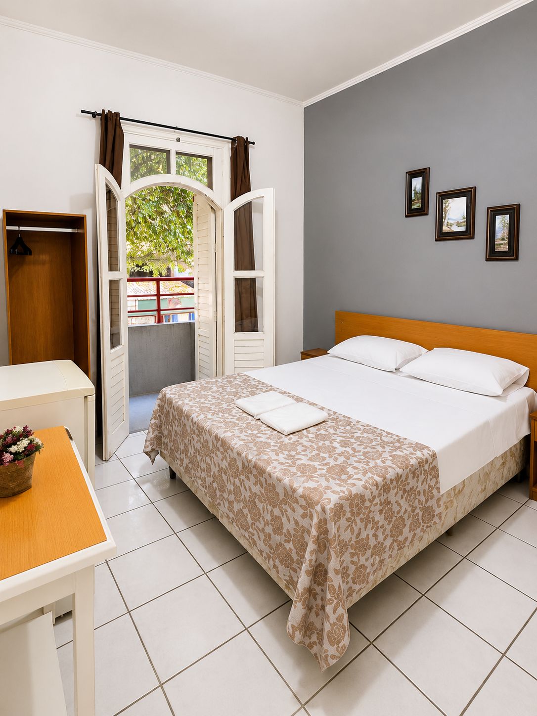 A hotel room with a bed, a desk, a chair, and a view of the outside.