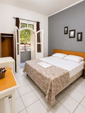 Habitación de hotel con cama, escritorio, silla y vistas al exterior.