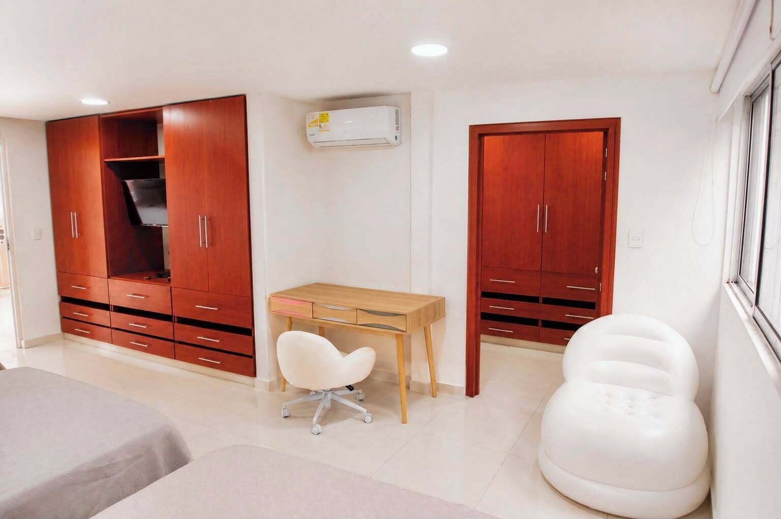 Un dormitorio con una cama, un escritorio, una silla y dos armarios.