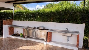 An outdoor kitchen with a stainless steel countertop, a sink, and a brick oven.