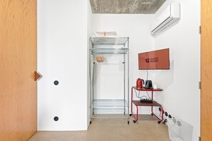 A hotel room with a metal rack, a red cart with a kettle and mug, and a 'GUEST READY' sign on the wall. - GuestReady - House of Many Faces - Room 4 (Porto)