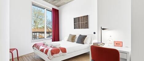 A modern bedroom with a bed, a desk, and a chair.