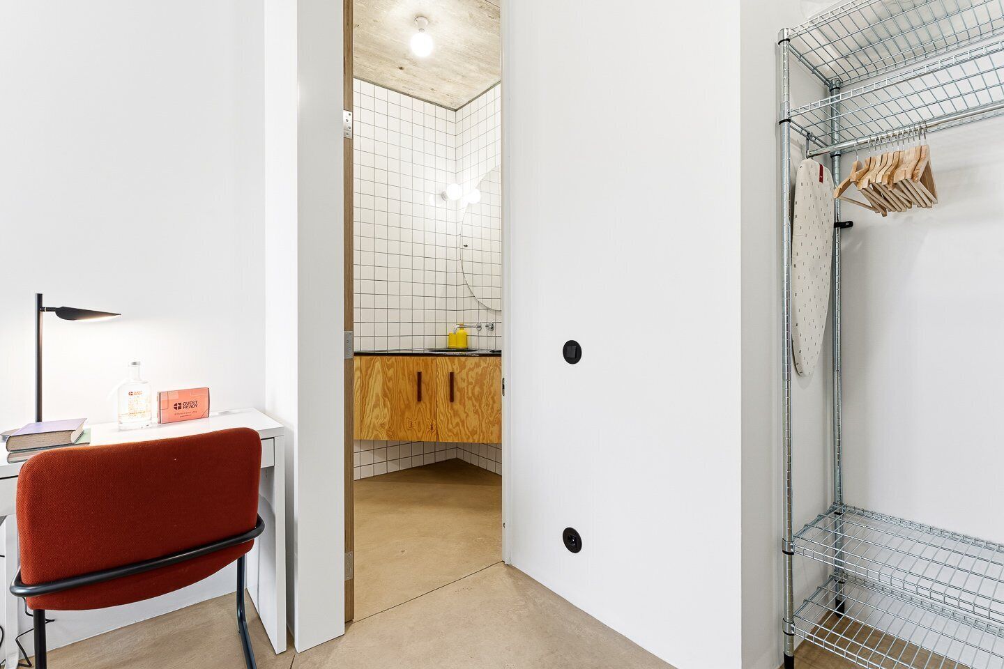A modern bathroom with a shower, a wooden cabinet, and a red chair.