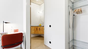 A modern bathroom with a shower, a wooden cabinet, and a red chair.