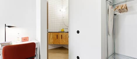 A modern bathroom with a shower, a wooden cabinet, and a red chair.