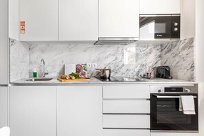 A modern kitchen with white cabinets, a Bosch microwave, a sink with a soap dispenser, and a pot on the counter. - GuestReady - Fantastic Porto Flat (Porto)