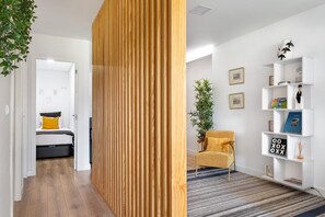 A modern living room with a wooden partition, a yellow armchair, a bookshelf, and a bed in the background. - GuestReady - Fantastic Porto Flat (Porto)