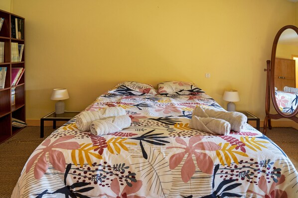 A hotel room with a bed, two bedside lamps, a wooden bookshelf, and a mirror.