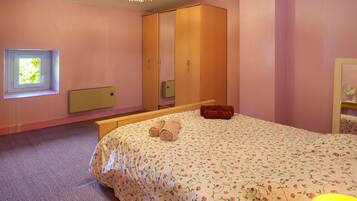 A bedroom with a bed, a wardrobe, a window, and a bedside table.
