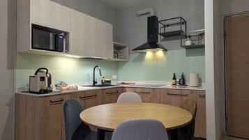 Una cucina moderna con un tavolo da pranzo rotondo, elettrodomestici integrati e una lampada a sospensione.