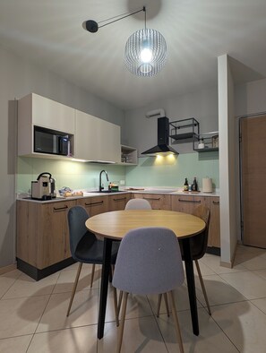 Una cucina moderna con un tavolo da pranzo rotondo, elettrodomestici integrati e una lampada a sospensione.