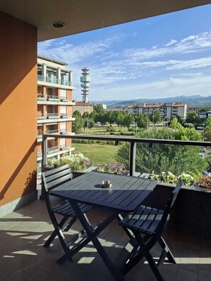 Un balcone con tavolo e sedie, vista su una zona residenziale con edifici e una torre.