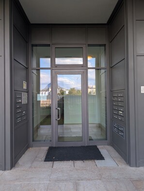 Un ingresso moderno con una porta in vetro, una maniglia in metallo e un tappetino nero.