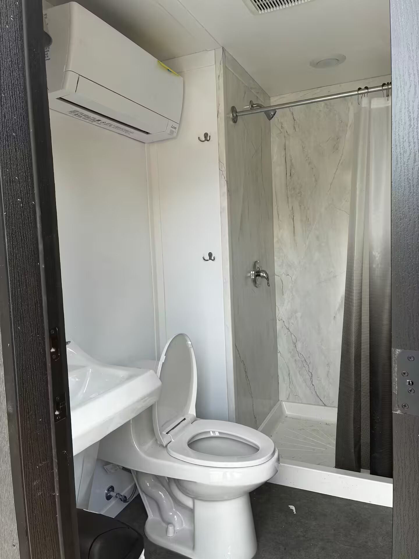 Un baño con inodoro, ducha y aire acondicionado.
