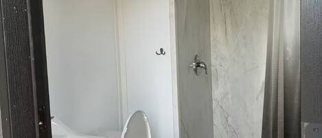 Une salle de bain équipée de toilettes, d’une douche et d’un appareil de climatisation.