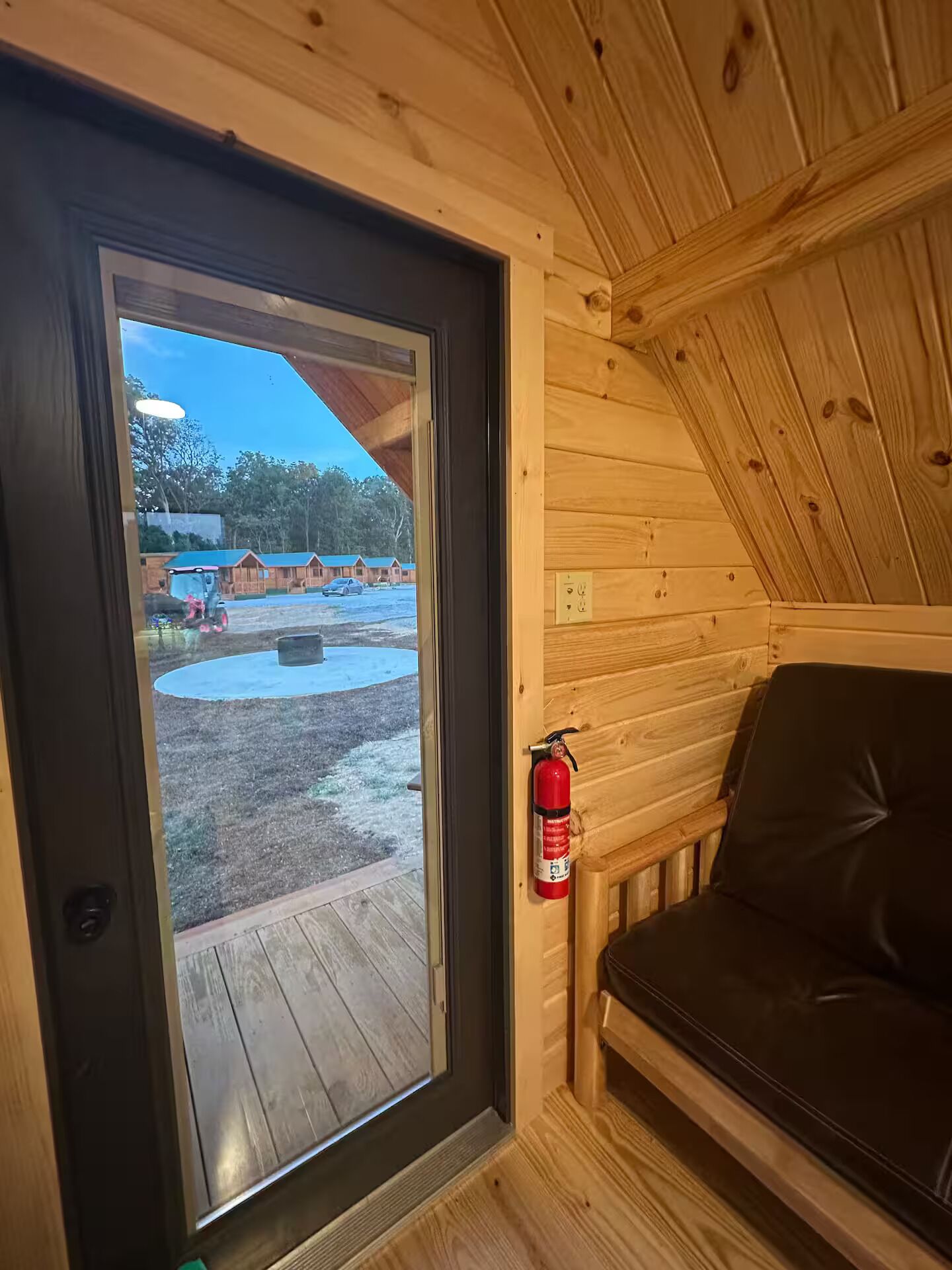 A wooden cabin interior with a sliding glass door leading to an outdoor area.