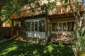 A covered outdoor seating area with a wooden deck, a stone wall, and a grassy lawn. - Ca la Calma, Palau-Saverdera (Palau-saverdera)