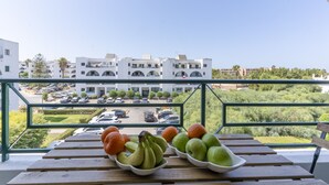 A balcony with a view of a modern building and a parking lot. - #413 Charming 1-Bedroom Apartment | Salgados, Albufeira (Albufeira)