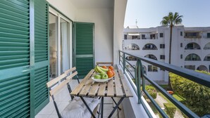 A balcony with a wooden table, a bowl of fruit, and a bench. - #413 Charming 1-Bedroom Apartment | Salgados, Albufeira (Albufeira)