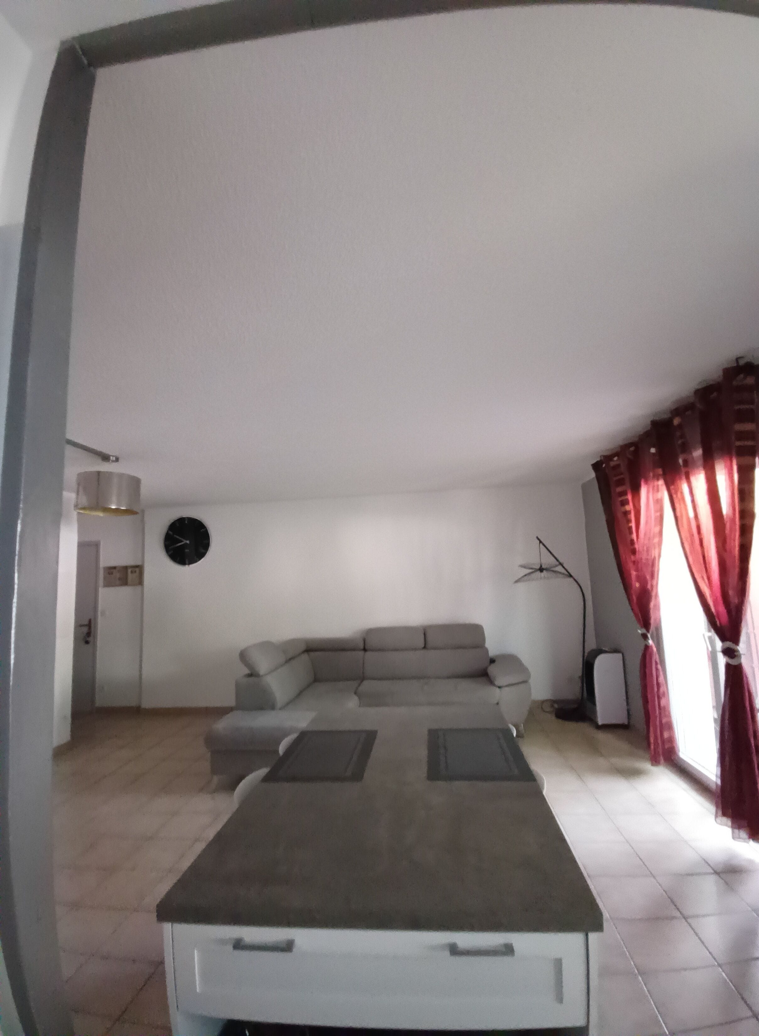 A living room with a sofa, a flat-screen TV, and a window with curtains.