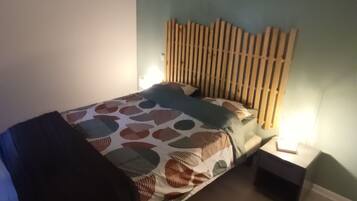 A single bed with a patterned bedspread, a wooden headboard, and two bedside lamps.