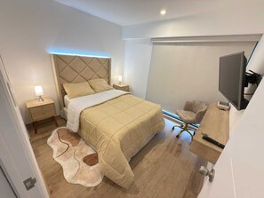 Une chambre à coucher avec un lit, des lampes de chevet, une télévision, une chaise et un tapis.