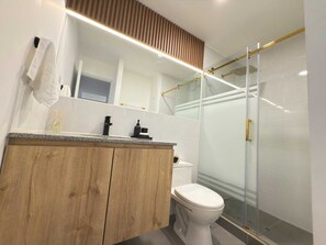 Une salle de bain moderne avec un meuble-lavabo en bois, des toilettes blanches et une cabine de douche en verre.