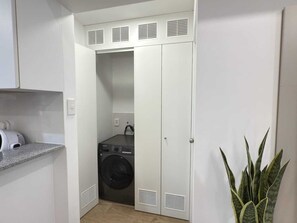 A compact laundry room with a washing machine, a dryer, and a plant. - Apartment in Lince, just a short walk from San Isidro—a pleasant, safe neighborhood where everything is nearby (Lima)