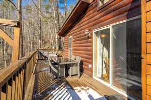 Una baita in legno con veranda, porte scorrevoli in vetro e mobili da esterno.
