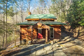 Una baita con tetto verde, un portico in legno e un sentiero di pietra che conduce all'ingresso.