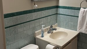 Un baño con inodoro, lavabo, espejo y toallero.