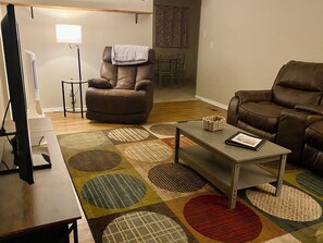 A living room with a brown leather sofa, a coffee table, and a TV.