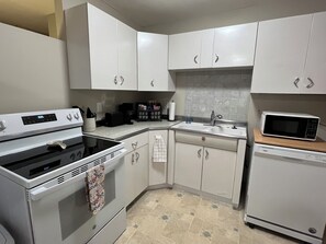 A kitchen with white cabinets, a stove, a microwave, and a dishwasher.
