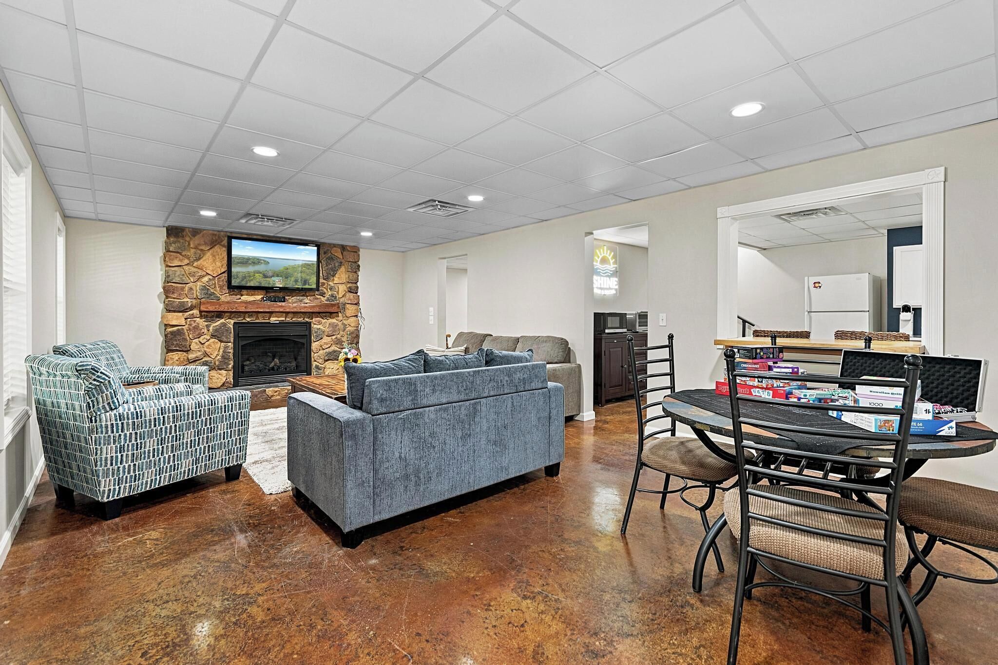 A spacious living area with a stone fireplace, a flat-screen TV, and a dining table with chairs.