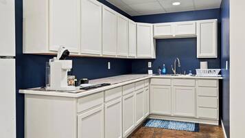 A kitchen with white cabinets, a built-in coffee maker, and a sink with a faucet.