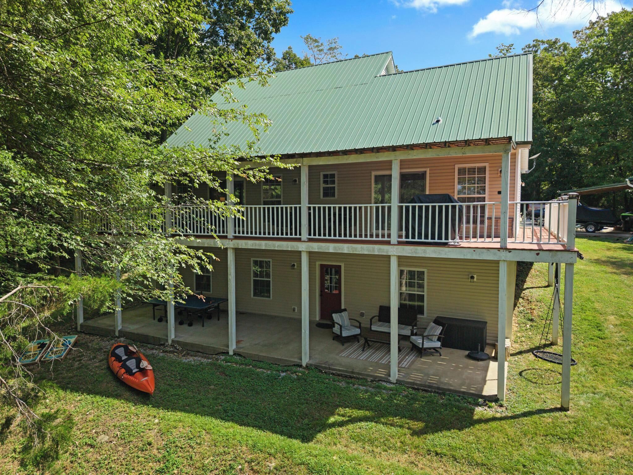 A two-story house with a balcony, outdoor seating, and a kayak.
