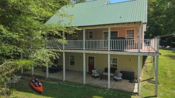 A two-story house with a balcony, outdoor seating, and a kayak.