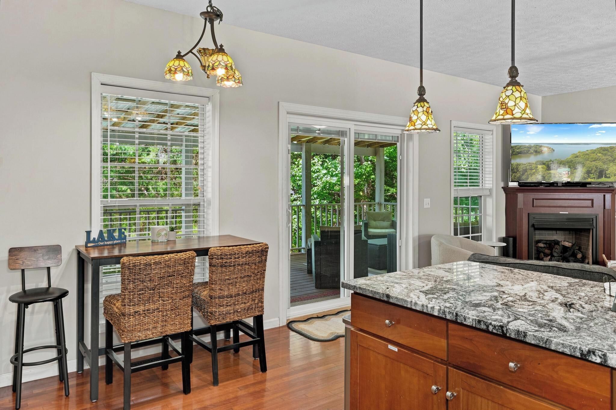 A kitchen with a marble countertop, wicker chairs, a dining table, and a fireplace.