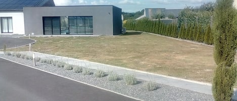 A modern building with a flat roof, large windows, and a well-maintained lawn.