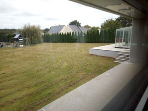 A view of a grassy yard with a concrete structure and a glass greenhouse. - Domaine d’architecte d'exception dans un ensemble moderne et sécurisé. (La Gravelle)