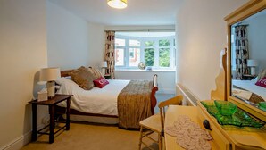 A hotel room with a bed, bedside table, lamp, chair, and a large mirror. - Host and Stay | BKL Seaview House (Colwyn Bay)