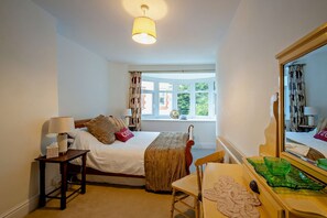A hotel room with a bed, bedside table, lamp, chair, and a large mirror. - Host and Stay | BKL Seaview House (Colwyn Bay)
