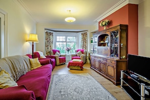A living room with a sofa, armchairs, a coffee table, a cabinet, and a television. - Host and Stay | BKL Seaview House (Colwyn Bay)