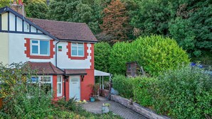 A two-story house with a red and white exterior, a front garden, and a small shed. - Host and Stay | BKL Seaview House (Colwyn Bay)