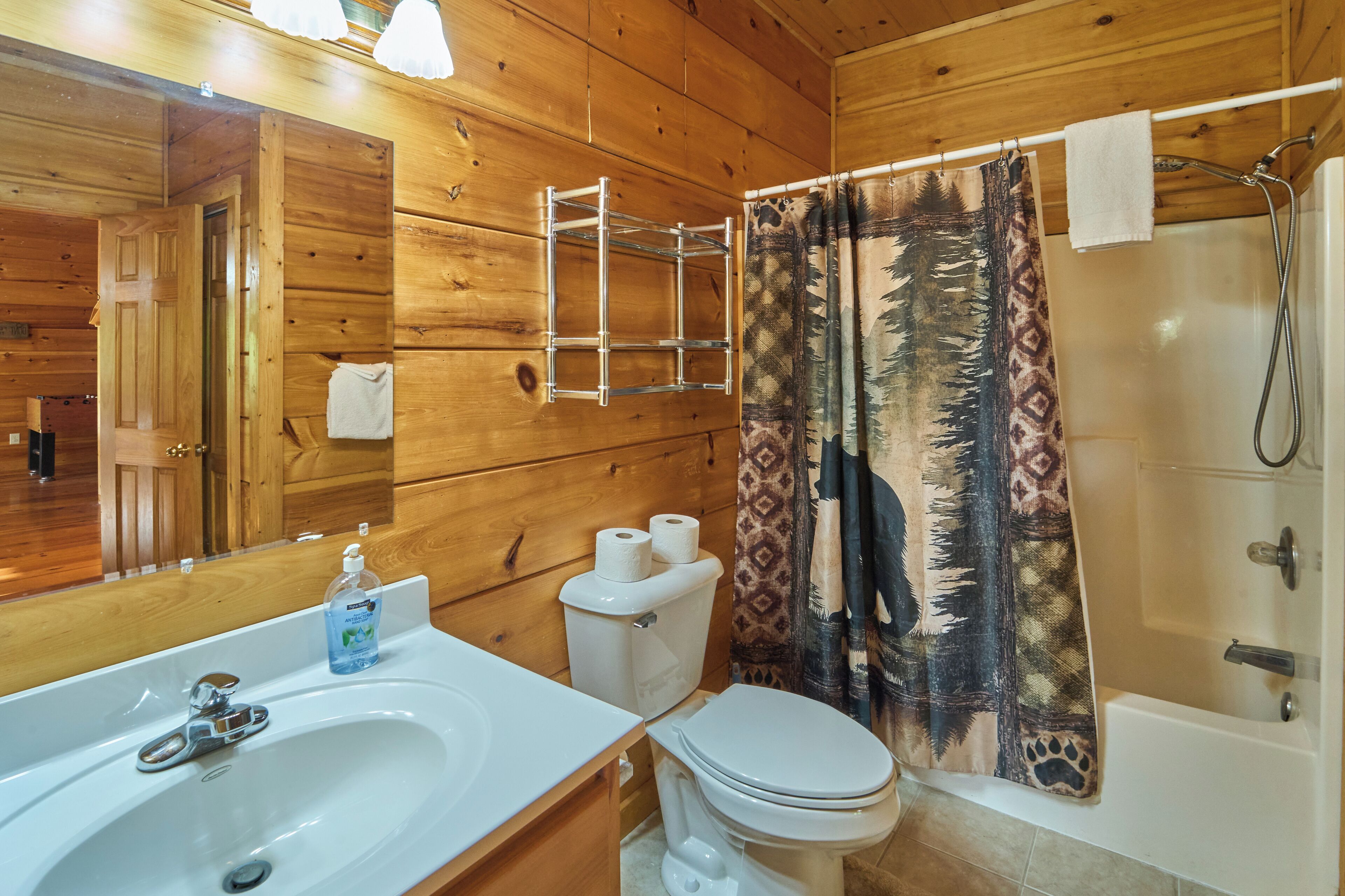 A wooden cabin bathroom with a sink, toilet, and shower.