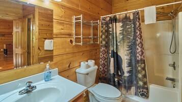 A wooden cabin bathroom with a sink, toilet, and shower.