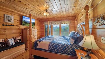 A wooden cabin bedroom with a bed, dresser, and a 'Welcome' sign.
