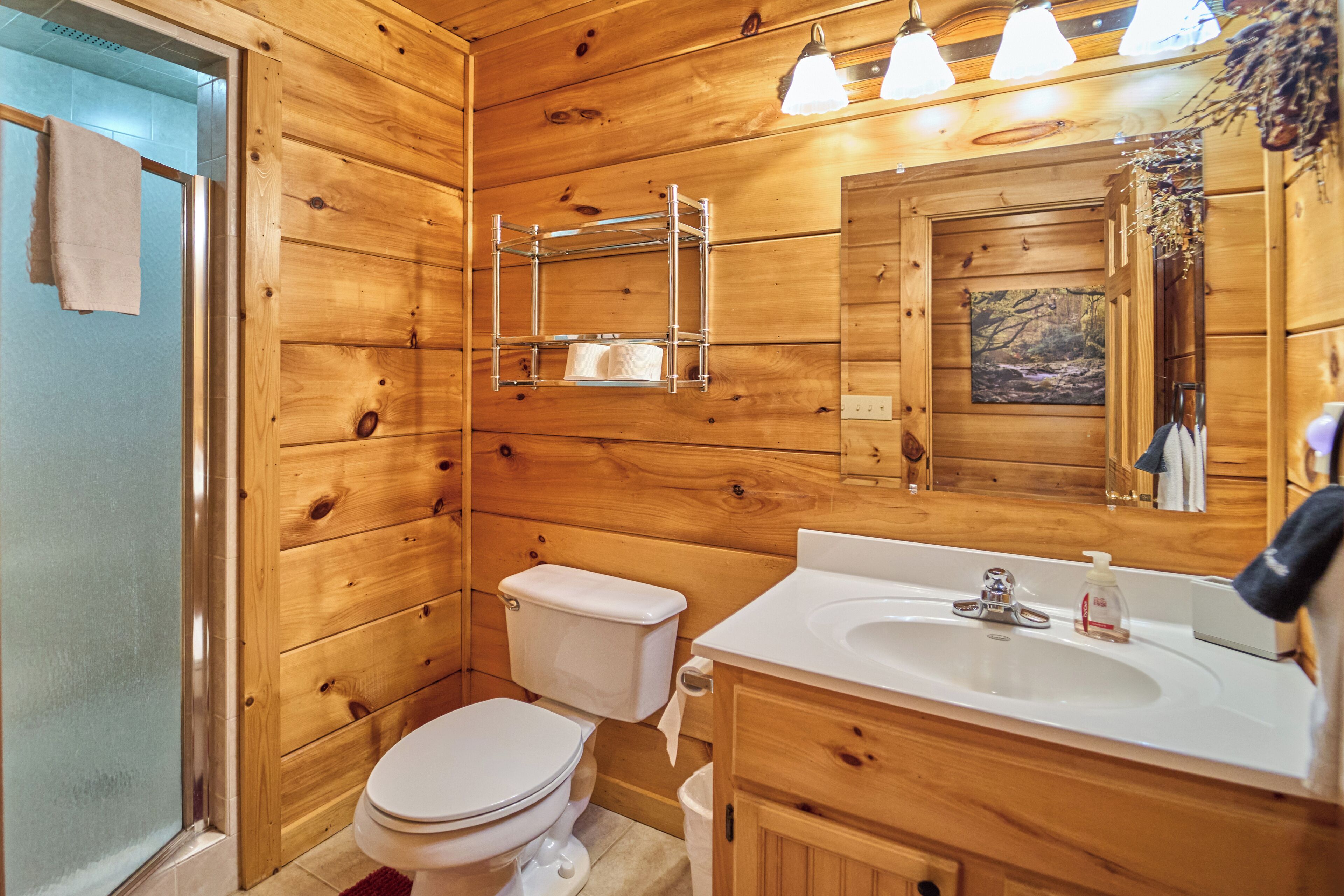 A wooden cabin bathroom with a toilet, sink, and mirror.